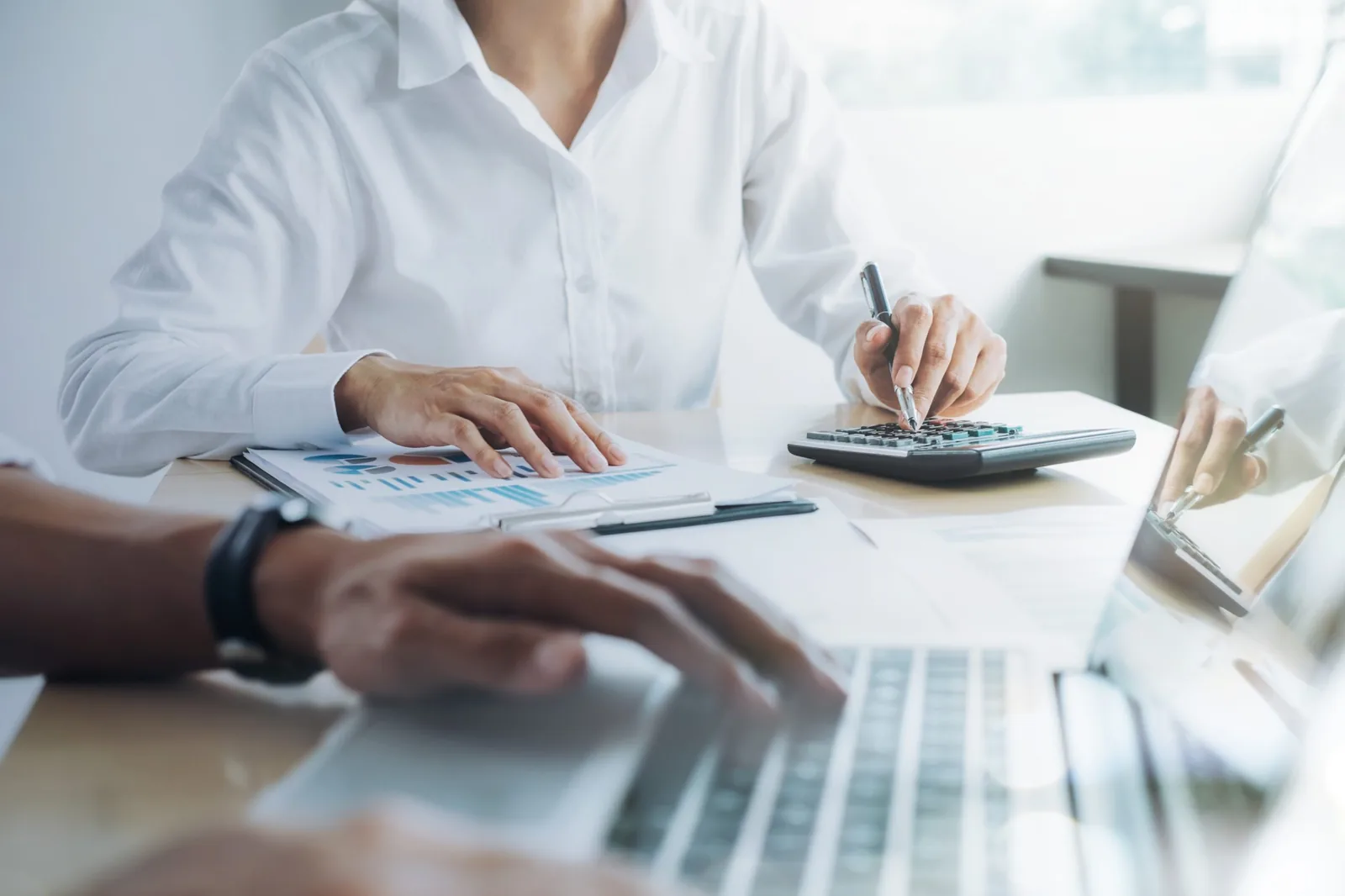 Professional accountant calculating payroll outsourcing costs and compliance benefits at modern office desk with calculator and financial reports