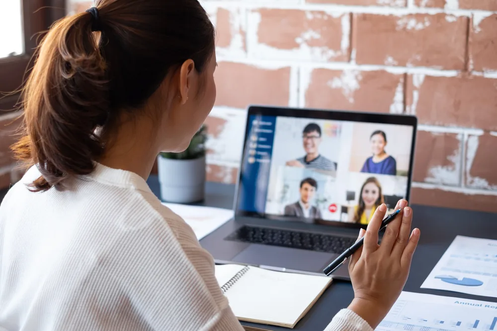Employee using HR software for remote teams in Pakistan during a virtual team meeting on a laptop.