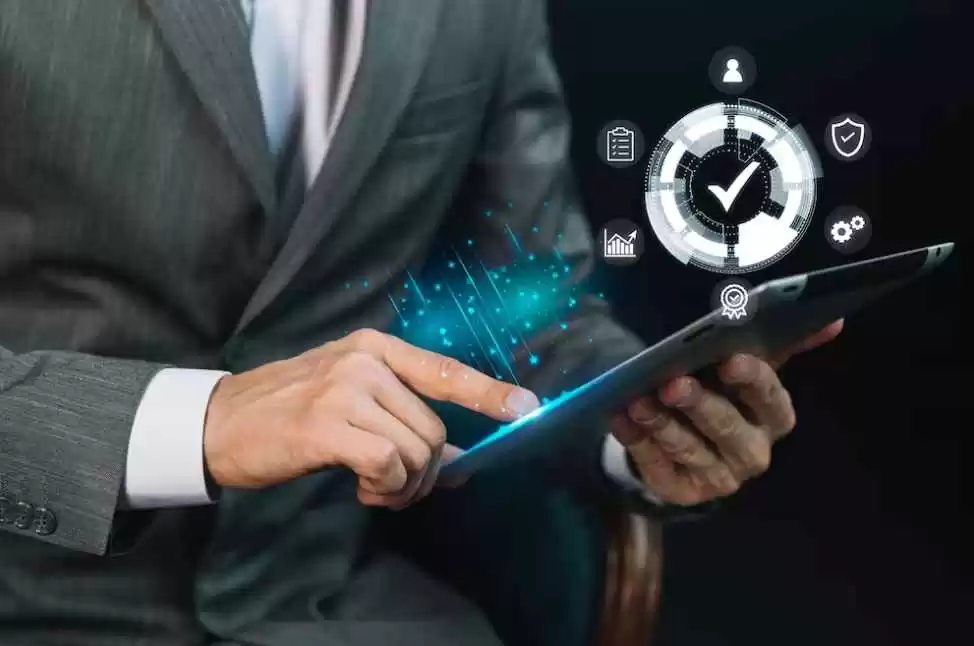 Business professional using a tablet with digital icons representing time tracking, workforce management, and data analytics overlayed.